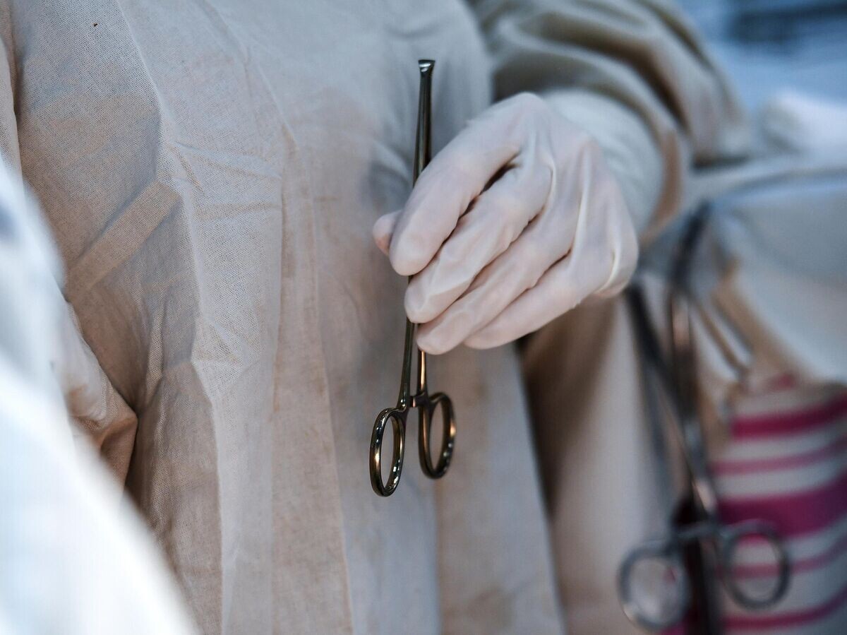    Хирург-гинеколог держит хирургический зажим во время операции© РИА Новости / Константин Михальчевский