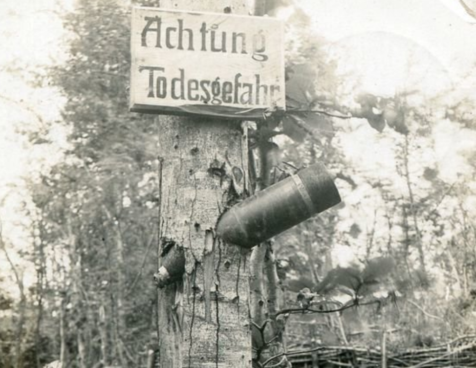 Табличка "Achtung todesgefahr (Внимание опасность для жизни)" и каким-то чудом не разорвавшийся крупнокалиберный снаряд застрявший в дереве, на которой она висит