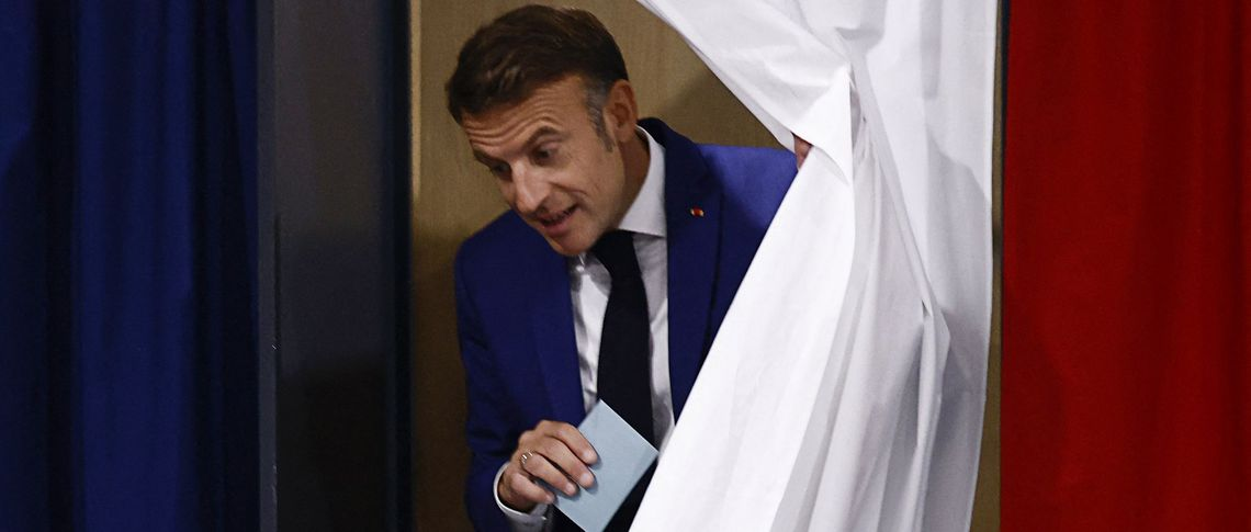 Президент Франции Эммануэль Макрон покидает кабину для голосования после голосования в первом туре досрочных парламентских выборов.