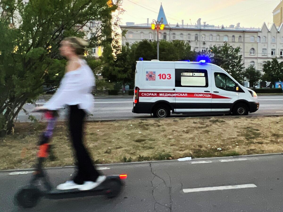    Девушка проезжает на самокате по тротуару недалеко от машины скорой помощи© РИА Новости / Наталья Селиверстова