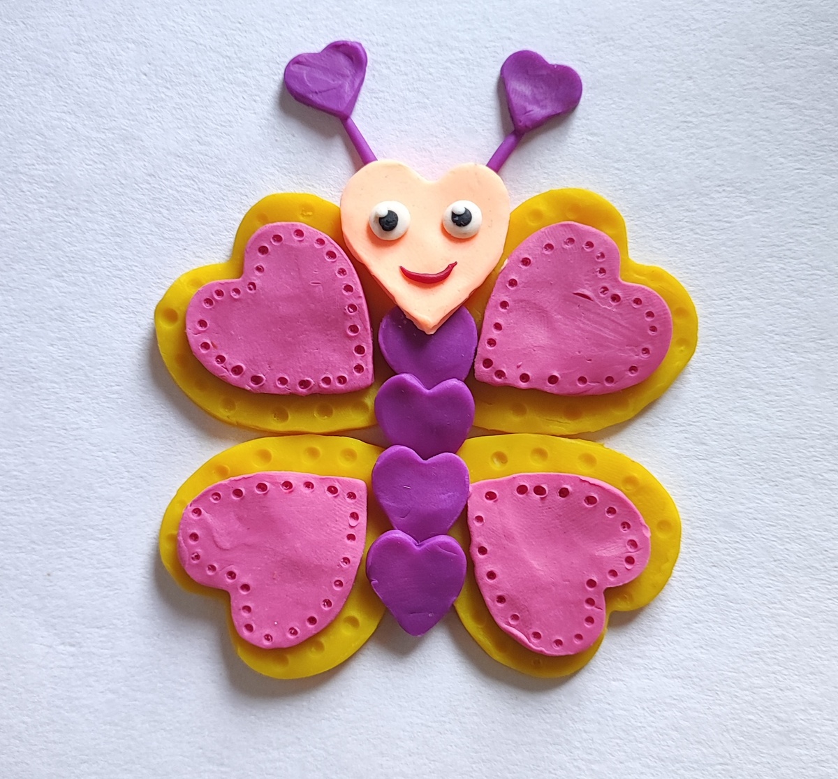 Готовый вариант аппликации из пластилина на картоне Бабочка из сердечек.