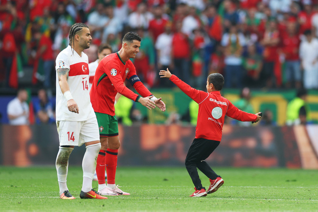    Криштиану Роналду приветствует на поле десятилетнего болельщика во время матча сборных Турции и Португалии. Getty Images