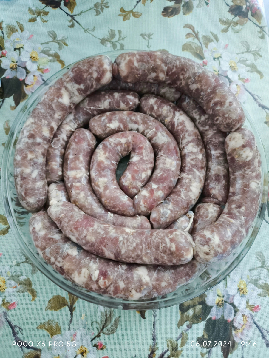 Тифлокомментарий. На столе стоит большое стеклянное блюдо с сырыми колбасками для жарки. По весу здесь 3 килограмма 400 граммов. 