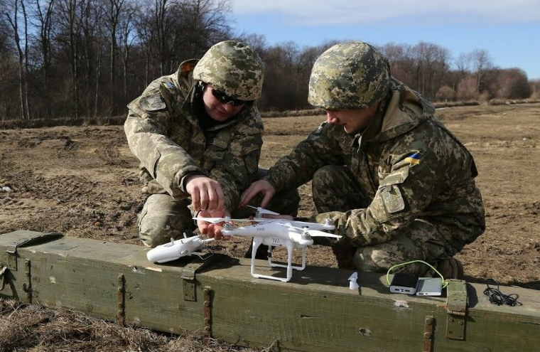 Молодые бойцы в полевых условиях мастерят боевой дрон.