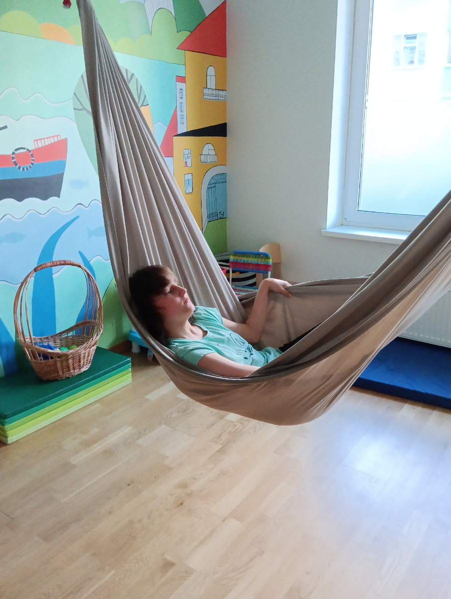 В гамаке. Проприцептивная нагрузка, сенсорная, тренирует вестибюлярку, успокаивает. 