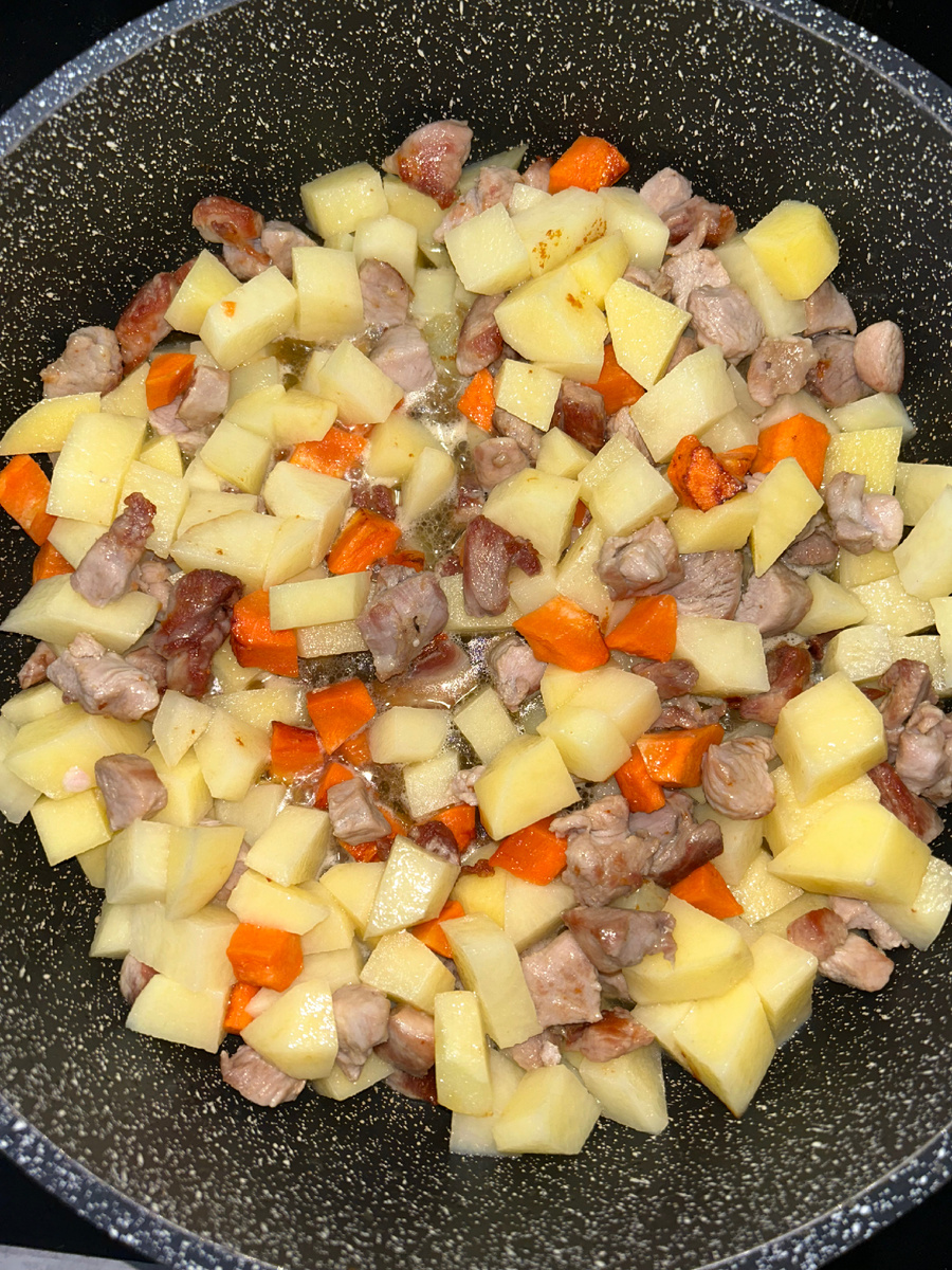 Берем филе бедра 500 грамм, нарезаем небольшими кусочками и обжариваем на сильном огне 10 минут. Потом добавляем нарезанный кубиками морковь среднюю и картофель 4-5 шт. Тушим минут 15.