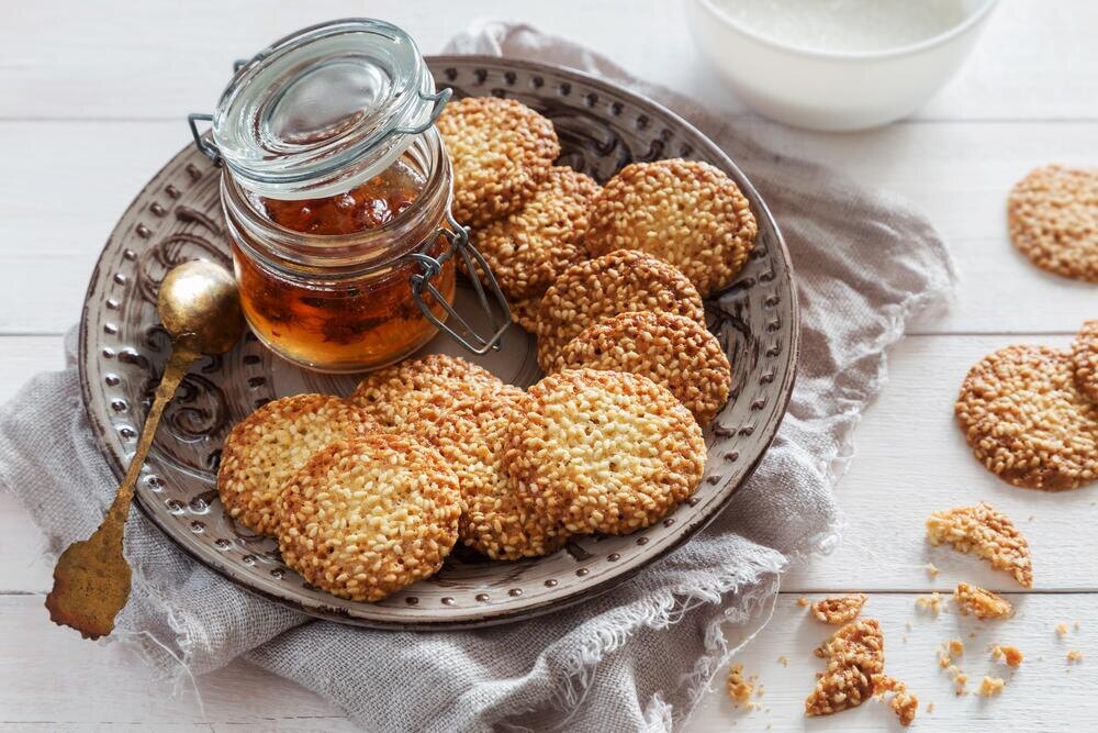 Печенье с кунжутом... Это настоящая маленькая симфония вкусов. Взгляните на него: нежные и хрупкие пластинки, украшенные золотистым кунжутом, словно звезды на голубом небе.