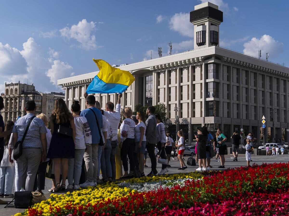    Группа людей с флагом на площади Независимости в Киеве© AP Photo / Jae C. Hong