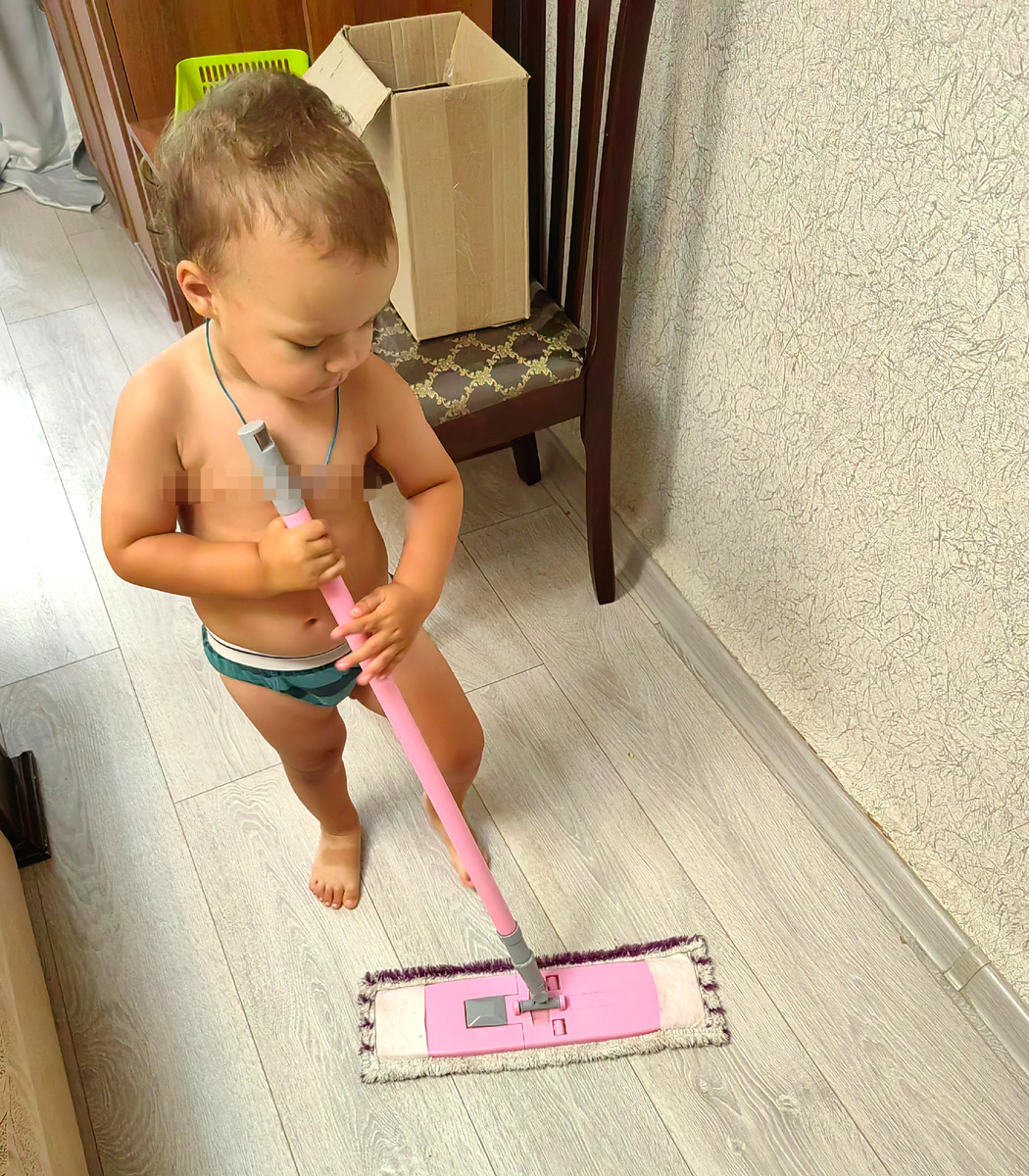Сын протирает пол перед распаковкой и примеркой одежды б/у