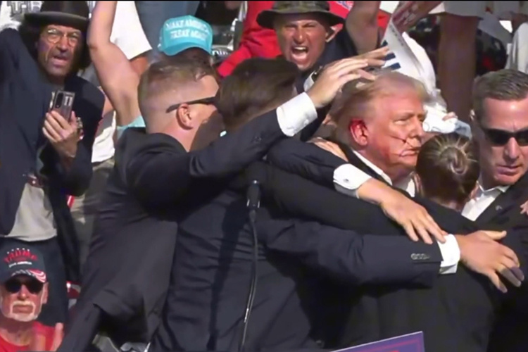    Дональд Трамп встречался с избирателями в городе Батлере, но его речь оборвали выстрелы. На видеокадрах, которые облетели весь мир, видно, как после звуков стрельбы политик хватается за правое ухо.   
Фото: © Hu Yousong/XinHua/www.globallookpress.com