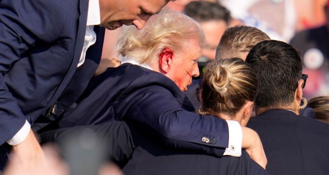 Раненого Дональда Трампа уводят со сцены.