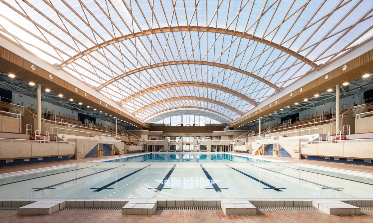 Переработка и повторное использование… бассейн Georges Vallerey, который будет использоваться для обучения плаванию, был оборудован новой раздвижной деревянной крышей. Фотография: Hugo Hebrard/AIA Life Designers – architectes.