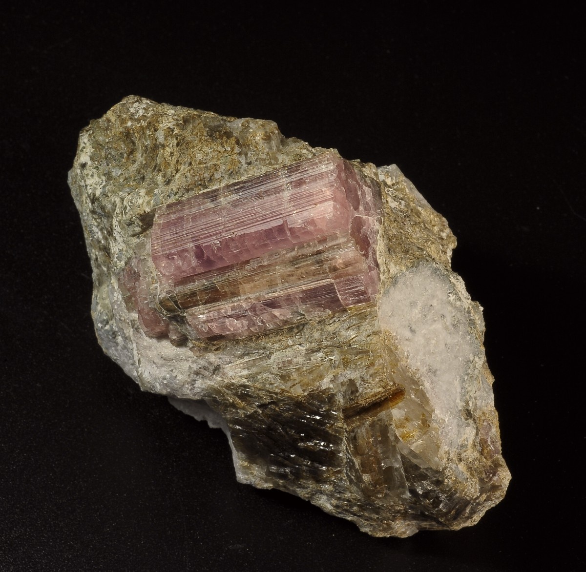 Розовый призматический кристалл шомиокита-(Y) размером 3,5 х 2 см на породе сложенной смесью троны и альбита. Образец из коллекции Гришина В.Г. Фотография: Лейбов М.Б.