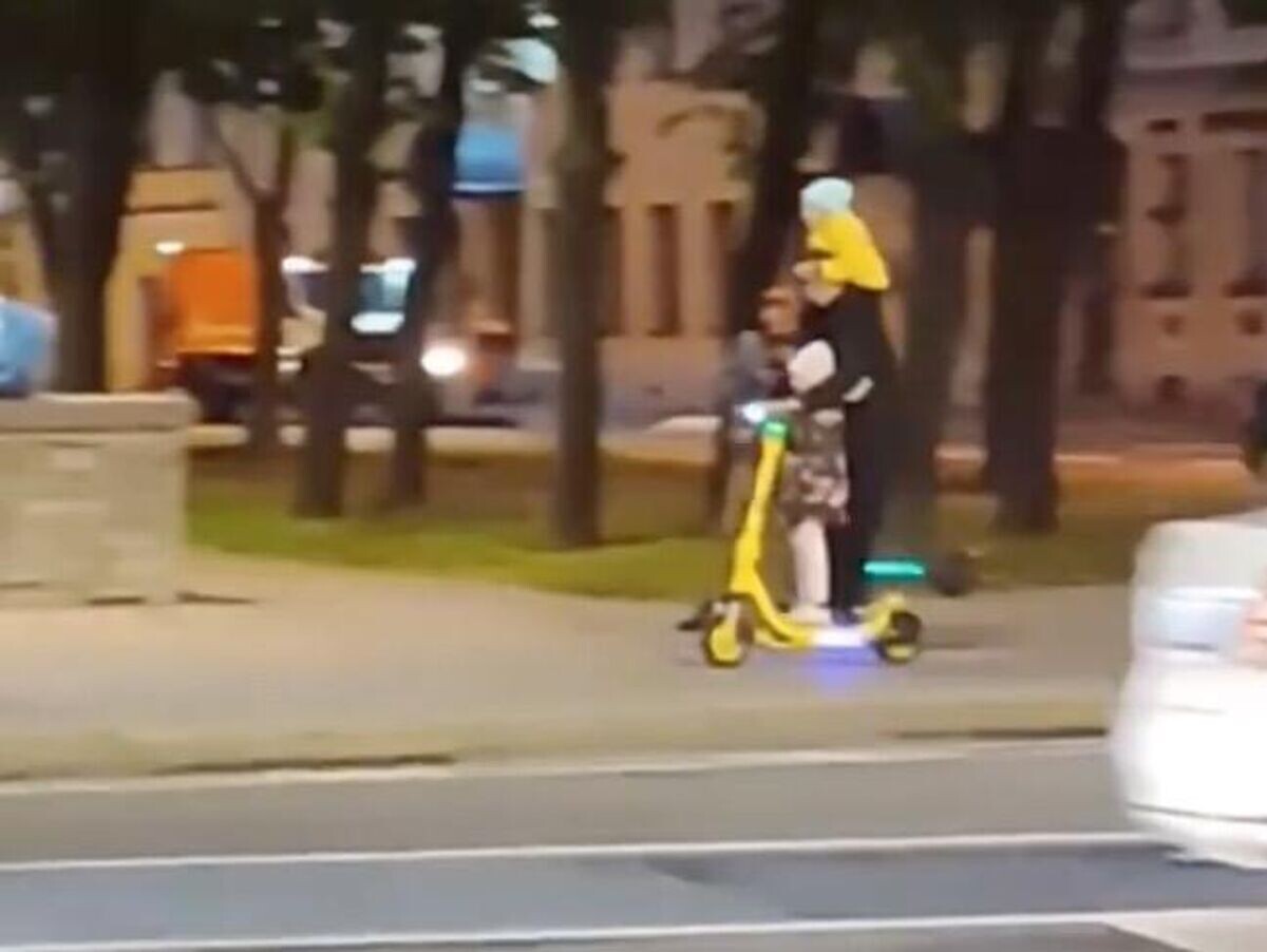    Мужчина едет на электросамокате с двумя детьми в Санкт-Петербурге© Кадр видео из соцсетей