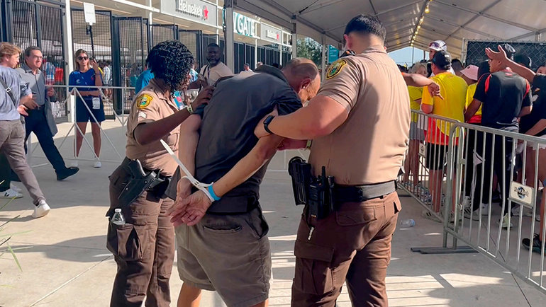    Полиция арестовывает одного из болельщиков. Reuters