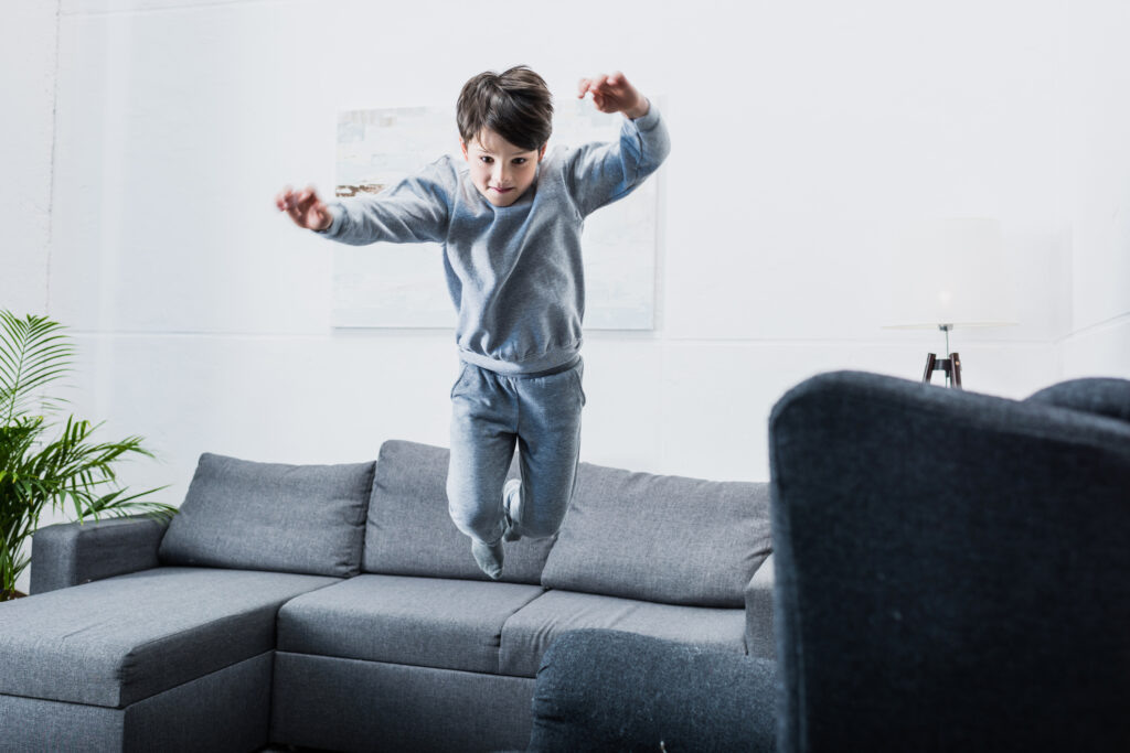    Cheerful little boy in pajamas jumping on couch at home Вячеслав Марченко