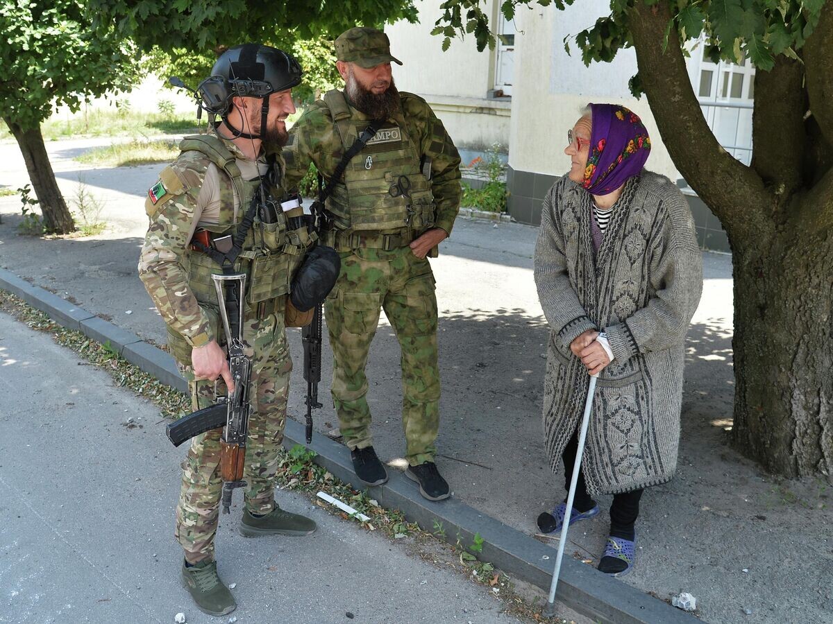    Бойцы специального полка полиции имени Героя России Ахмата-Хаджи Кадырова и жительница Лисичанска© РИА Новости / Виктор Антонюк