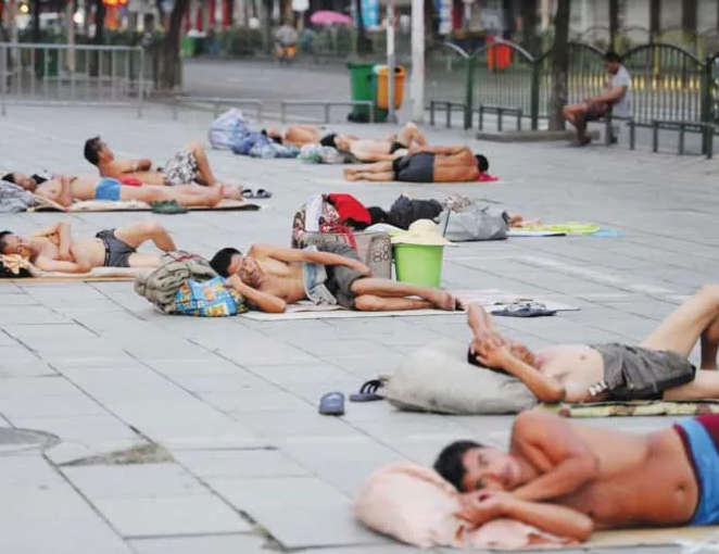 Рабочие мигранты спят рано утром в парке в жаркий месяц