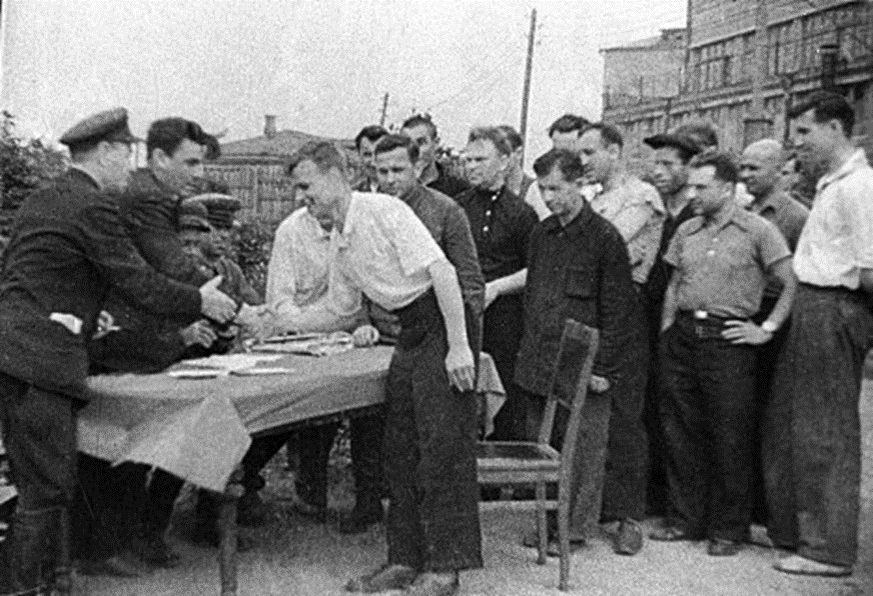 Где-то в СССР в 1941 года,сотрудники военкомата жмут руку добровольцу,который записался на фронт.