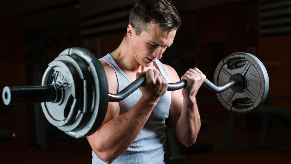 Подъём штанги на бицепс с изогнутым (EZ) грифом. Фото взято из интернета: https://clck.ru/3BymJ3