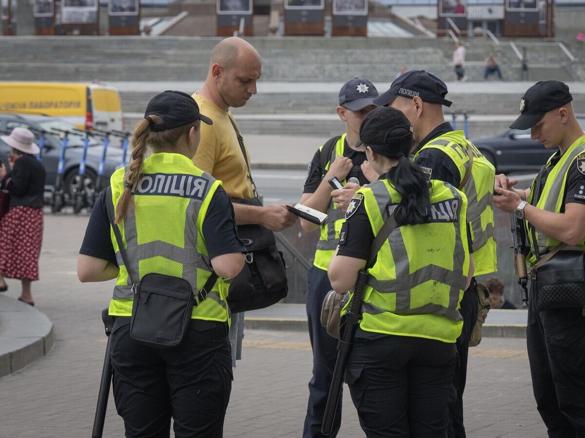    Сотрудники полиции Украины проверяют документы у мужчины на улице Киева© AP Photo / Efrem Lukatsky
