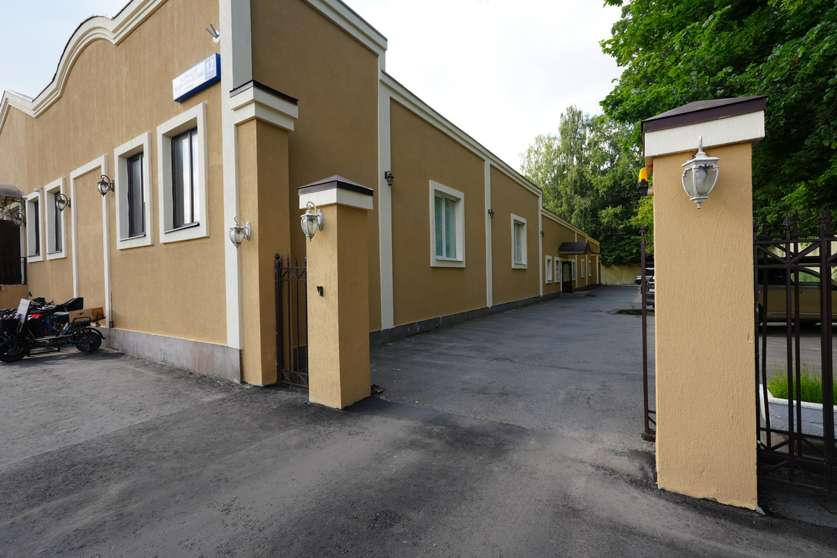 Ворота справа от здания, а за ними вход с торца здания