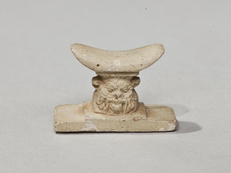 Фаянсовый амулет-подголовник с ножкой в форме головы бога Бэса. Древний Египет, II тыс. до н.э. Из коллекции ГМИИ им. А.С. Пушкина