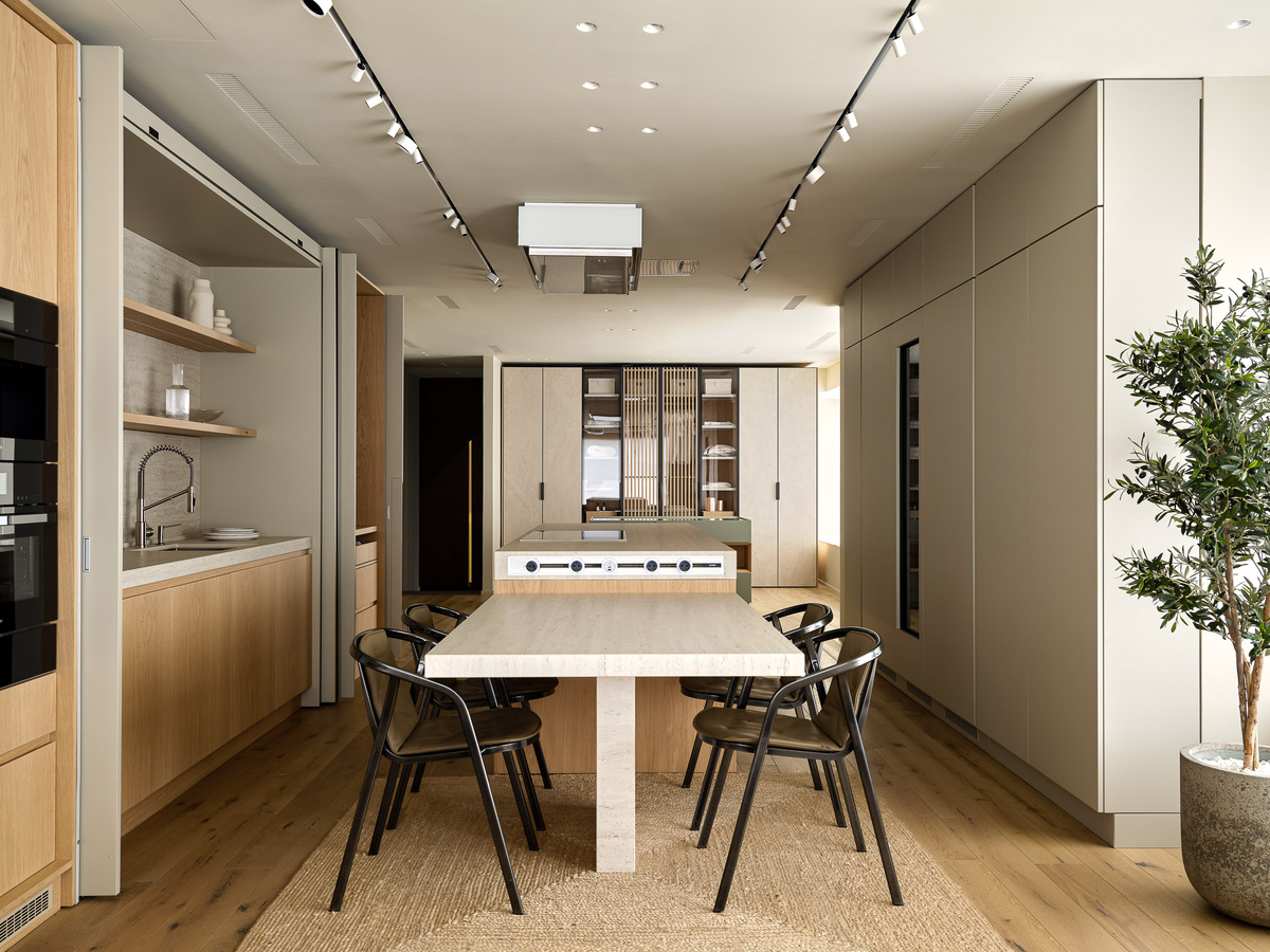 Композиционным центром является кухонный остров. Слева и справа от него вдоль стен расположили два ряда колонн, один из которых оснащен комбинаций блоков с задвижными фасадами. В закрытом виде они создают впечатление декоративной стены, в открытом – полностью функциональны и не мешают передвижению по кухне. 