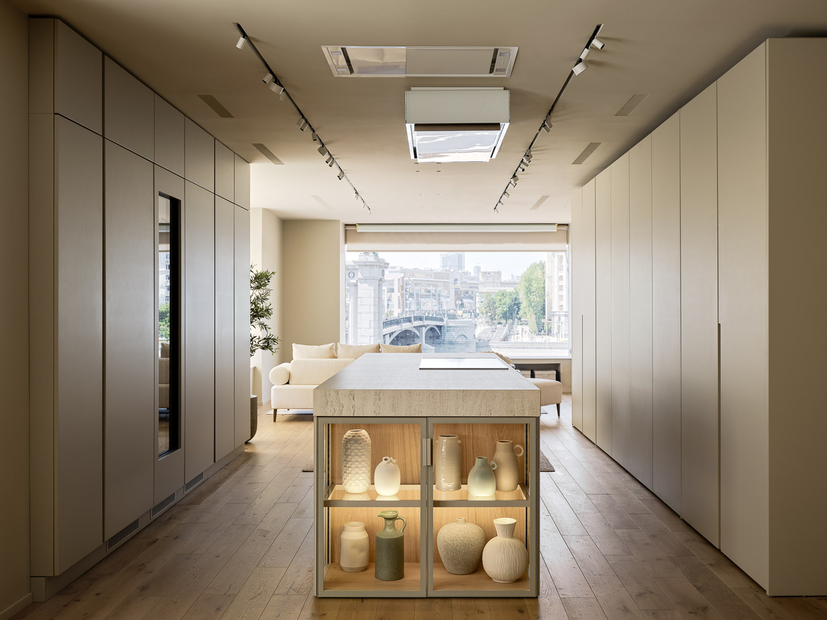 Композиционным центром является кухонный остров. Слева и справа от него вдоль стен расположили два ряда колонн, один из которых оснащен комбинаций блоков с задвижными фасадами. В закрытом виде они создают впечатление декоративной стены, в открытом – полностью функциональны и не мешают передвижению по кухне. 