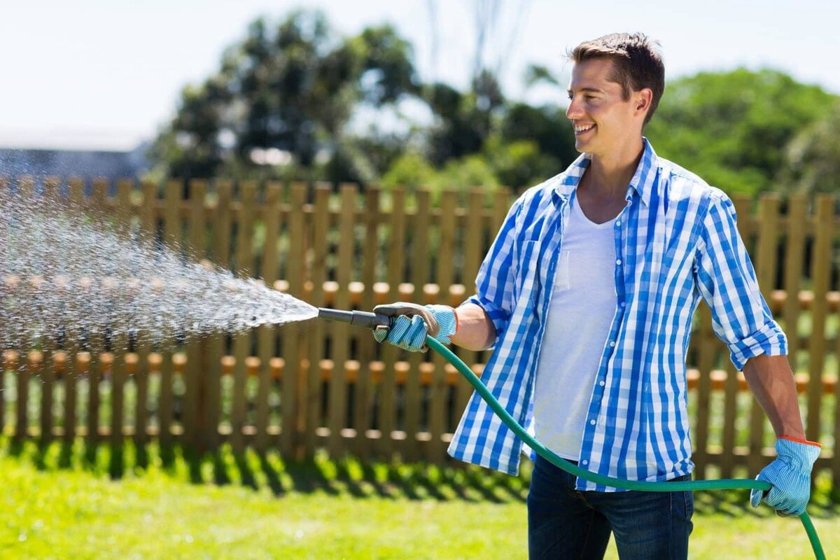 Мужчина поливает огород.