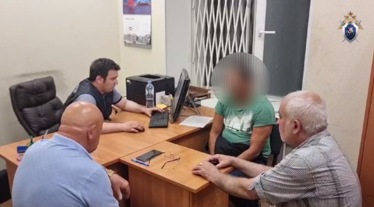 Обвиняемый (лицо закрыто) рядом с переводчиком (справа). Фото: СК Санкт-Петербурга.