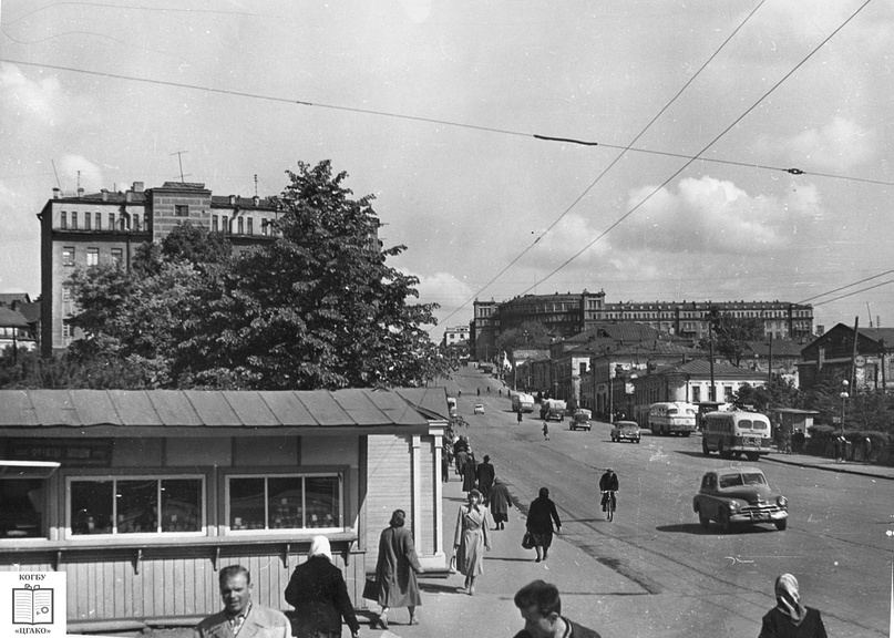 Справа вдали — Центральная гостиница (построена по проекту И. А. Чарушина в 1937 г.), слева — т.н. «Дом Чекистов» (построен по проекту И. А. Чарушина в 1939 г.) на углу Ленина и Герцена улиц (дом №79). На первом плане слева — ларек «Фрукты-овощи». г. Киров. 1964 г. Фото: ЦГАКО.