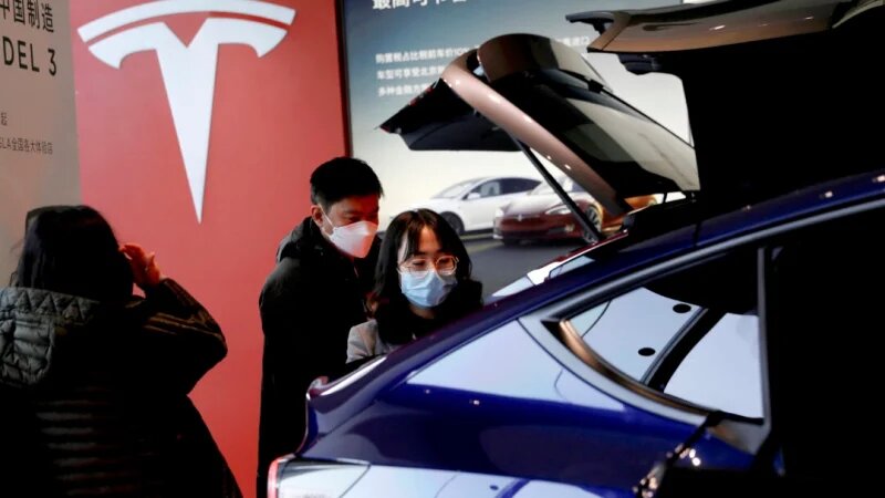 Посетители проверяют спортивный внедорожник Tesla Model Y китайского производства в выставочном зале производителя электромобилей в Пекине 5 января 2021 года. (Tingshu Wang/Reuters)