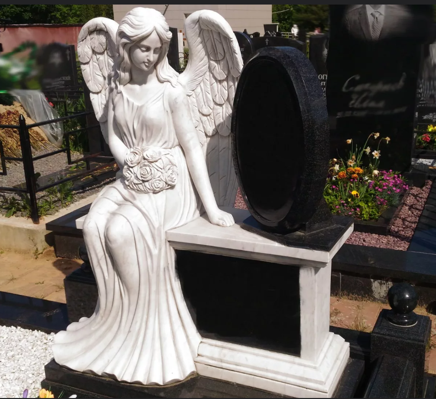 Скульптура ангела, выполненная из белого мрамора (коелга), совмещенная с памятником из черного гранита, породы габбро-диабаз.