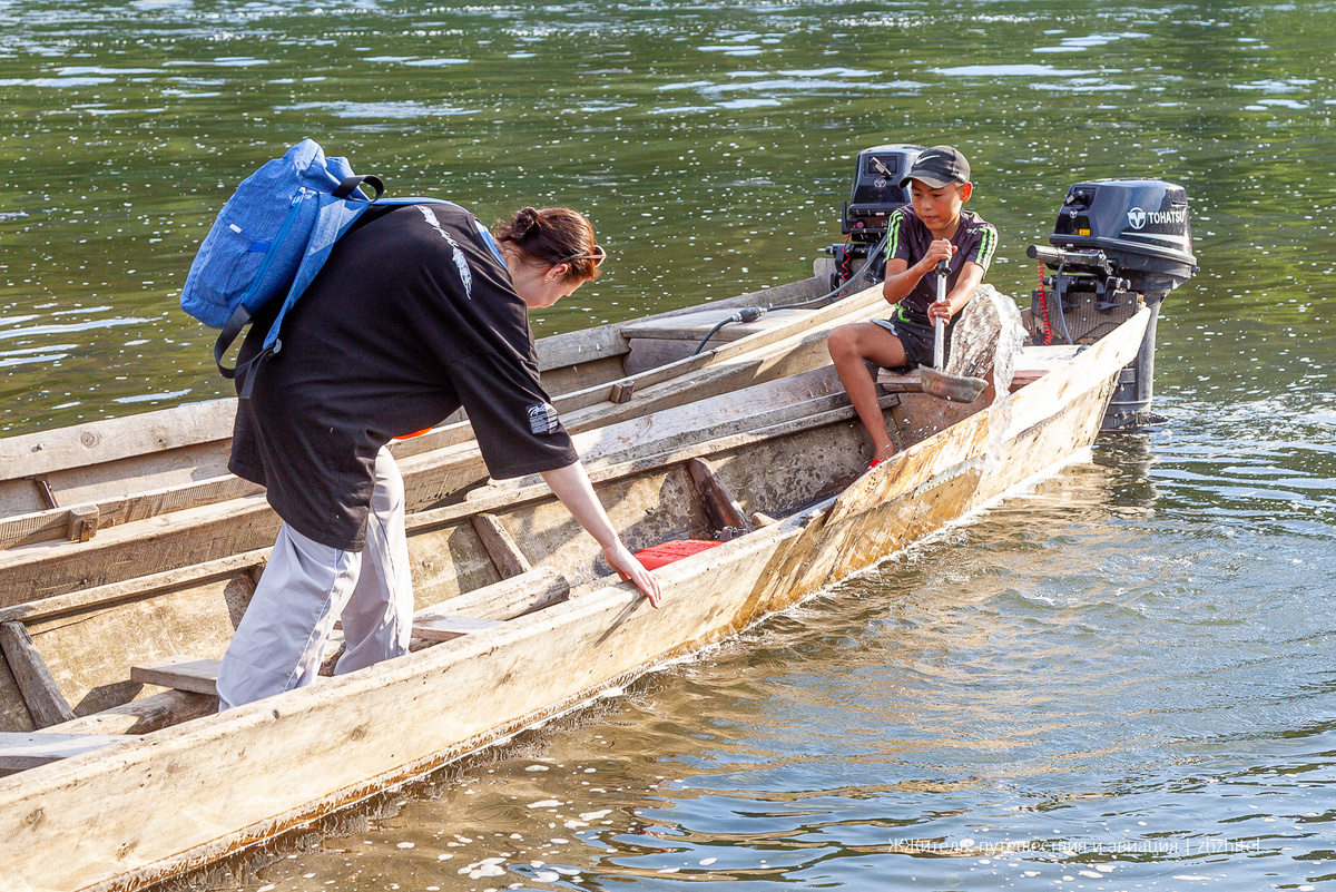 Мальчик перевозит туристов через реку