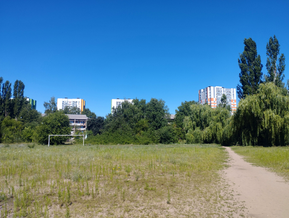 Студенческий городок ВГТУ, дорога через футбольное поле, за воротами общежитие, за ним новые дома
