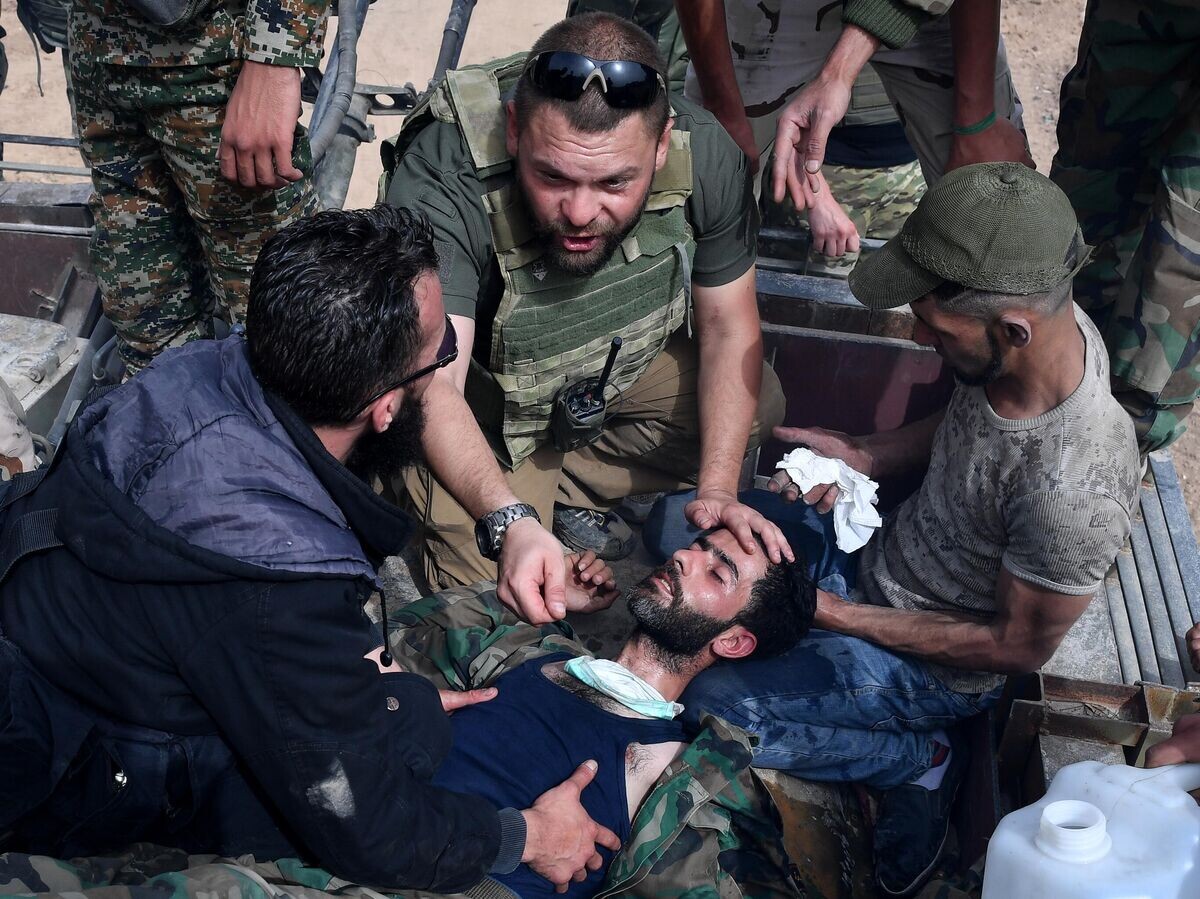    Военный журналист телеканала "Россия-24", специальный корреспондент ВГТРК Евгений Поддубный (в центре) оказывает первую медицинскую помощь пострадавшему военнослужащему на одной из улиц в районе бывшего лагеря палестинских беженцев Ярмук в южном пригороде Дамаска© РИА Новости / Михаил Воскресенский