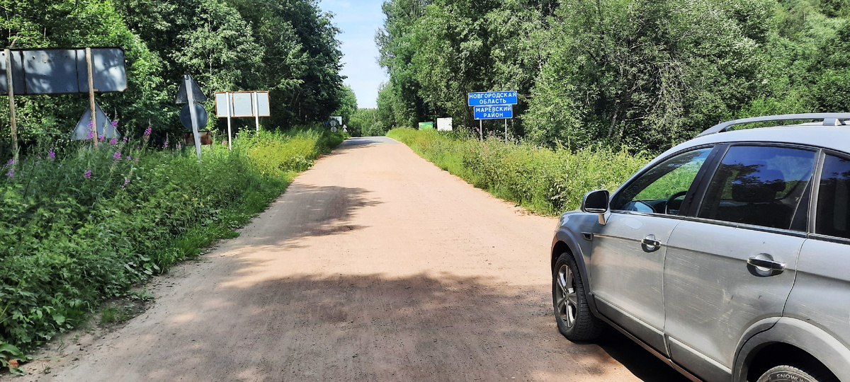 Я остановился перед синим указателем, на котором написано: Новгородская область, Марёвский район. Угадывается граница дорог с различным покрытием. Я пока еще в Тверской области. 