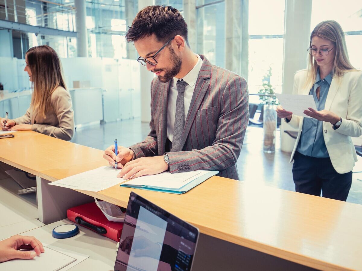    Мужчина подписывает документы в банке© iStock.com / LukaTDB