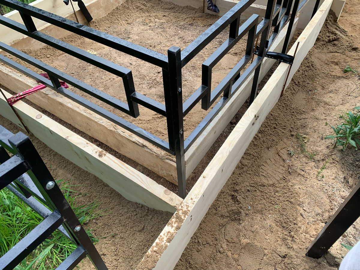 Подготовленная опалубка для заливания бетонного основания, с уже выставленной оградой