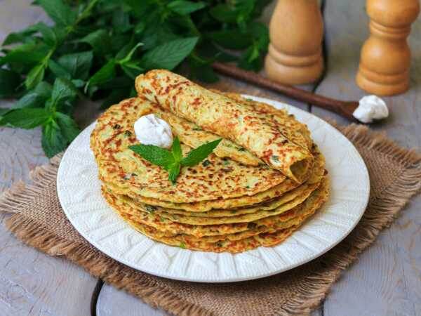 Румяные, легкие и вкусные кабачковые блины со свежей зеленью и сыром фета - прекрасный вариант сытного перекуса для всей семьи.