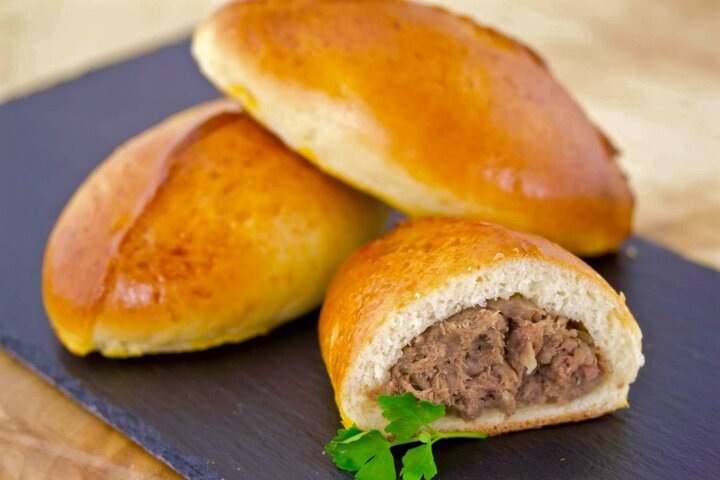 Пирожки выпечные на сдобном тесте с мясомКлассический вариант пышных и сдобных пирожков с начинкой из отварного мяса. Это лучшее выпечное изделие для подачи к бульонам или негустым супам, отличная закуска или сытный перекус.Для начинки правильнее выбрать говядину, причем от не самых премиальных отрубов. Лучше всего подойдет мясо от подбедерка, грудинки, шеи и даже от голяшки.Мясо от этих отрубов требует довольно длительной варки. Но именно оно получается самым нежным, ароматным и обладает именно тем самым вкусом, который запомнил каждый из нас, когда ел самые вкусные пирожки с мясом.Лук для добавления в мясной фарш обязательно поджарьте на сливочном или топленом масле. Именно оно придаст пирожкам аппетитный сливочный аромат и знакомый сладковатый вкус.В данном рецепте в тесто для пирожков добавляется небольшое количество соды. Этот прием делает тесто очень пушистым и нежным. Пирожки долго не черствеют и сохраняют красивый вид в течение 2-3 дней. Но для того чтобы сода не «подсушивала» тесто, а у нее имеется такое негативное свойство, обязательно добавляйте при замесе масло и сметану требуемой жирности. Иначе пирожки могут получиться крошливыми и суховатыми.