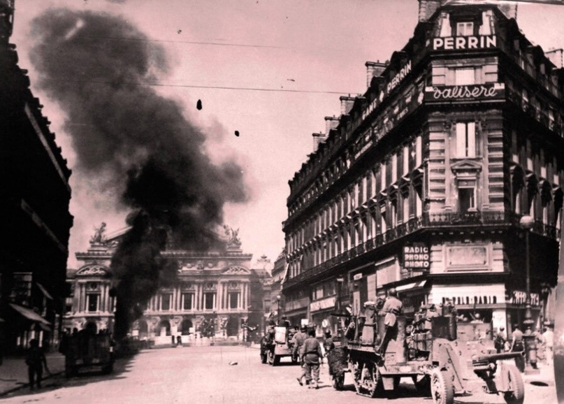 Освобождение Парижа, Франция, 25 августа 1944 года. Бронетехника дивизии Леклерка ведёт бой перед зданием Оперы. Один немецкий танк, подбитый ею, уже горит.