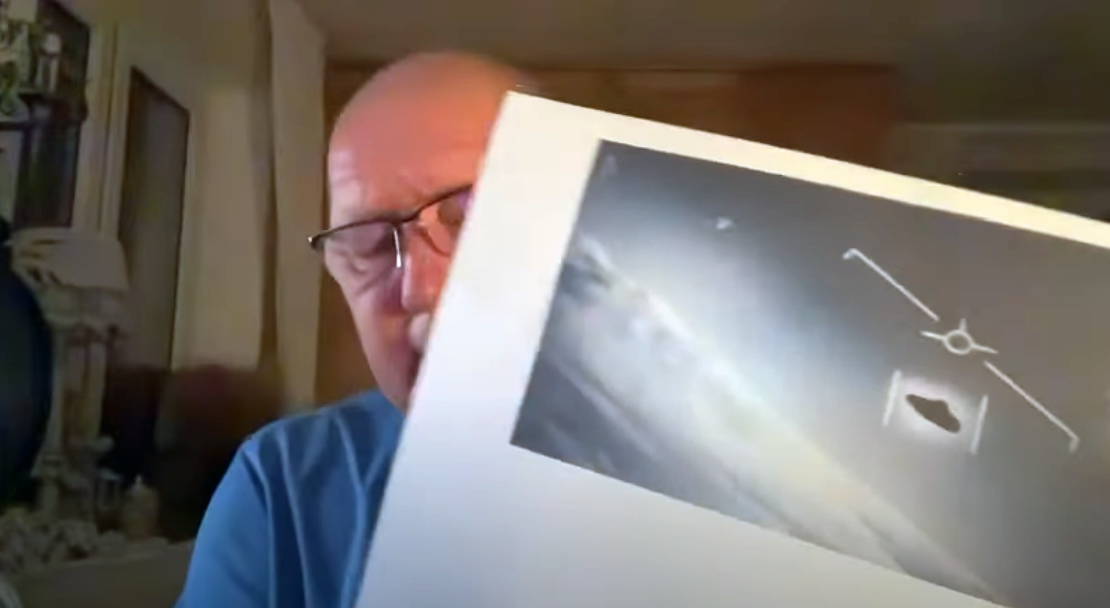 Момент онлайн-трансляции от 07 мая 2024 года. Кшиштоф Яцковский держит в руках фотографию НЛО, зафиксированного камерой военного самолета США у города Джексонвилл, атлантическое побережье штата Флорида, 20 января 2015 года. 