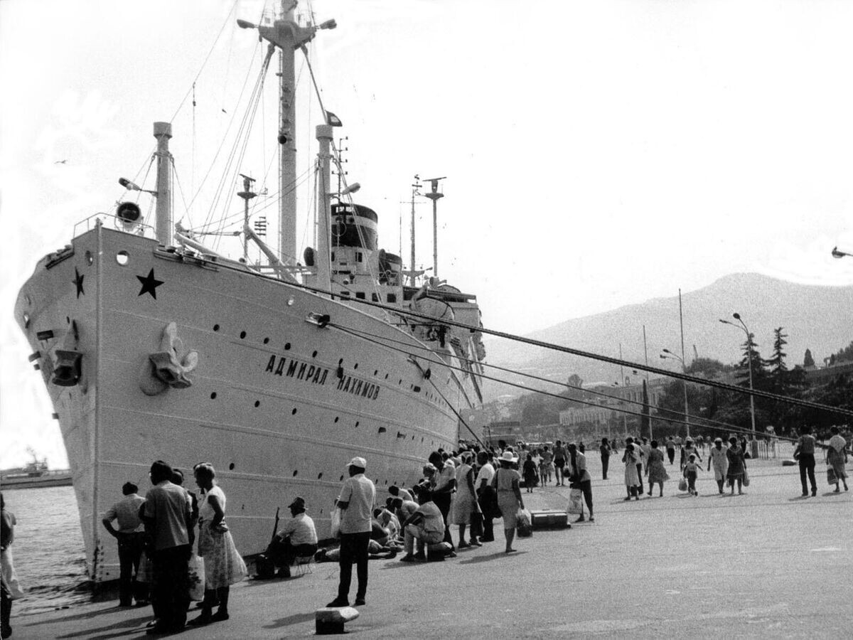    Лайнер "Адмирал Нахимов" у пирса в Ялтинском порту за сутки до гибели при столкновении с сухогрузом Петр ВасевCC BY-SA 4.0 / SergBuilo / The liner Admiral Nakhimov in the Yalta port a day before his death in a collision with the bulk carrier Peter Vasev (cropped)