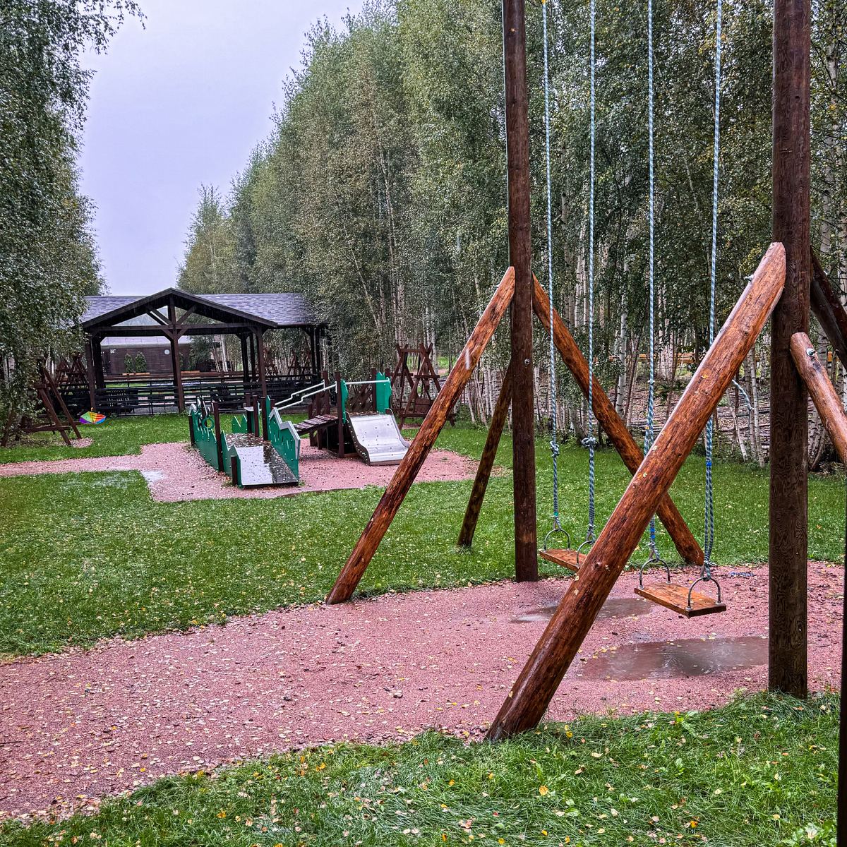 Качели рядом с игровой площадк для детей.