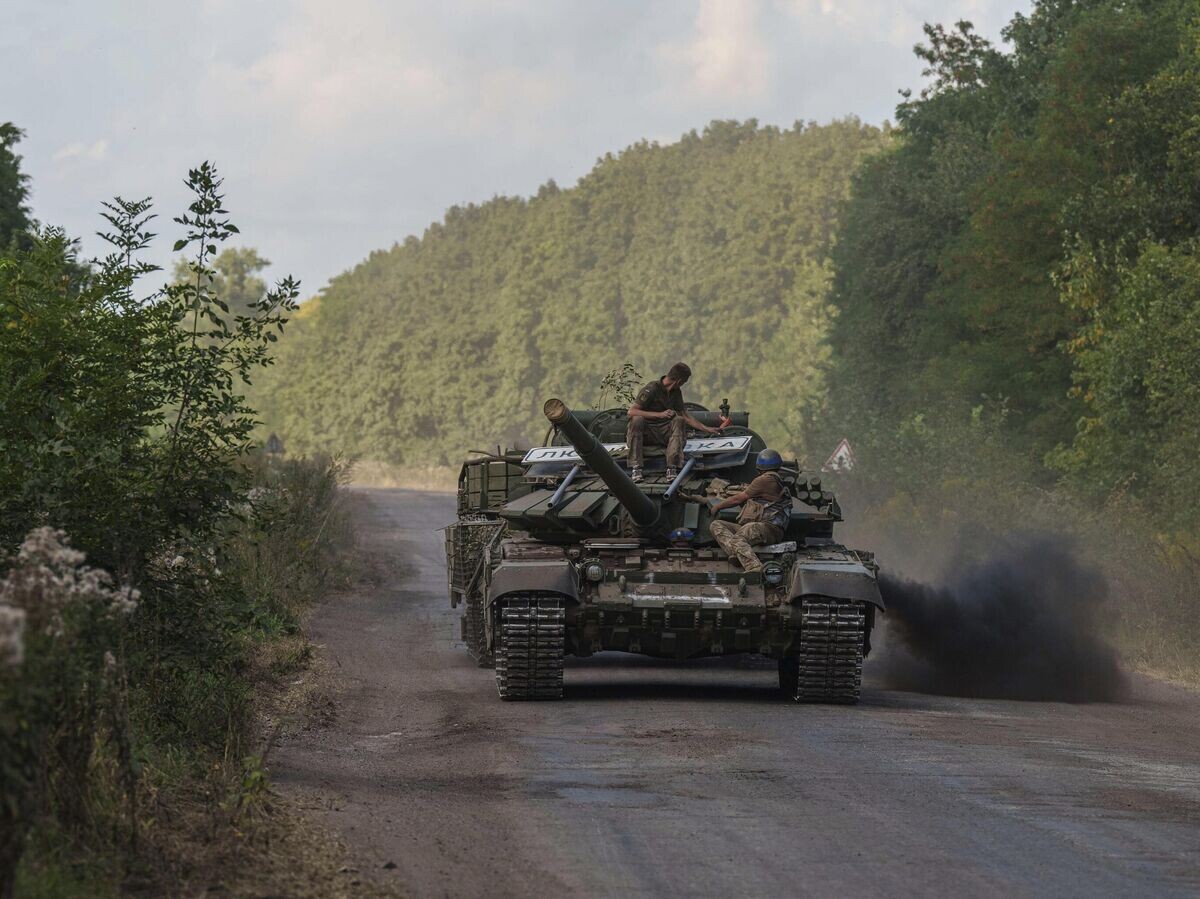    Украинские военнослужащие едут на танке с табличкой "Любимовка" недалеко от российско-украинской границы в Сумской области© AP Photo / Evgeniy Maloletka