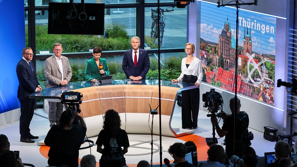 Главный кандидат от Христианско-демократического союза (ХДС) Марио Фойгт, премьер-министр Тюрингии Бодо Рамелов, главный кандидат от правой партии «Альтернатива для Германии» (AfD) Бьорн Хекке и главный кандидат от немецкого альянса «Буенднис Сара Вагенкнехт» (BSW) Катя Вольф стоят в телестудии с ведущей Мелани Хаак в день проведения выборов./ Wolfgang Rattay / REUTERS.
