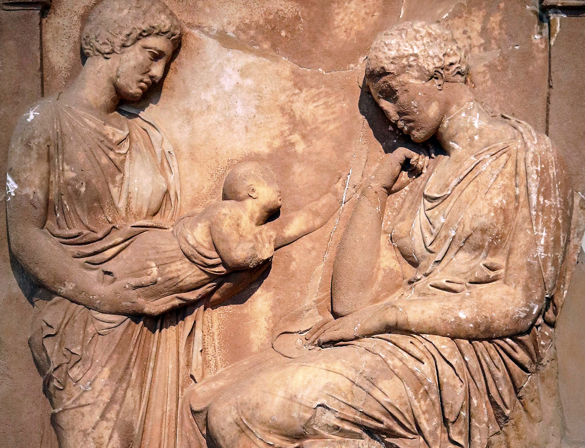Рельеф на надгробии умершей женщины. Молодая мать, сидящая на стуле, печально смотрит на своего младенца, которого держит другая стоящая женщина и протягивает его матери. Афины. IV в. до н.э.