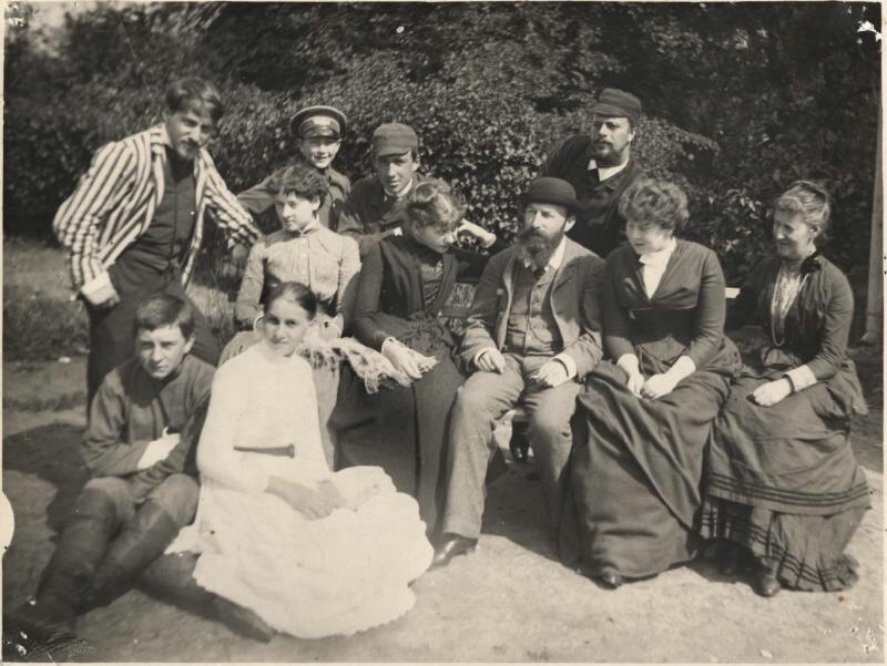 Фотография. Абрамцево, в саду возле теремка. В.А. Серов стоит слева, опершись на край скамьи; одет в полосатую куртку. Перед ним на земле сидят А.С. и О.Ф. Мамонтовы. На скамье сидят (слева направо): М.Ф. Якунчикова, Н.А. Мамонтова, П.А. Спиро, С.Ф. Тучкова и m-elle Рашу. Стоят за скамьей: С.П. Спиро, В.С. Мамонтов, Ю.Н. Фрей. Слева виден угол дома. На фоне кустов и деревьев. Из собрания Музея-заповедника "Абрамцево"
